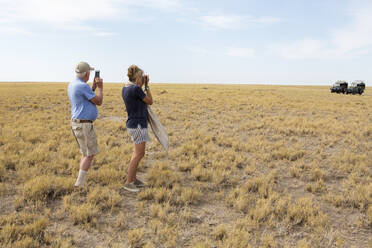 Familie beim Beobachten von Erdmännchen, Kalahari-Wüste, Makgadikgadi-Salzpfannen, Botswana - MINF14986