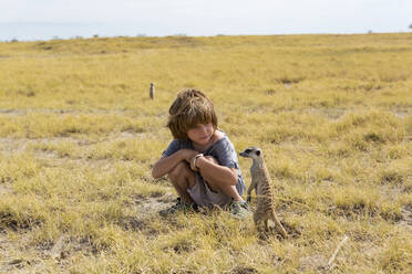 5 Jahre alter Junge beobachtet Erdmännchen, Kalahari-Wüste, Makgadikgadi-Salzpfannen, Botswana - MINF14988