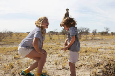 5 Jahre alter Junge mit Erdmännchen auf dem Kopf, Kalahari-Wüste, Makgadikgadi-Salzpfannen, Botswana - MINF14991