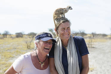 Erwachsene Frau mit Erdmännchen auf dem Kopf, Kalahari-Wüste, Makgadikgadi-Salzpfannen, Botswana - MINF14992