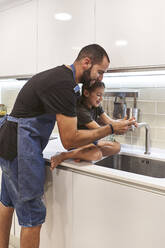 Father and daughter washing hands in kitchen sink at home - VEGF02577