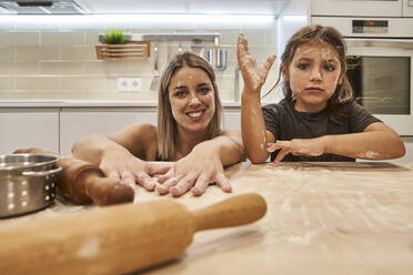 Verspielte Mutter und Tochter mit unordentlichen Gesichtern sitzen am Tisch in der Küche - VEGF02607