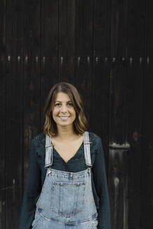 Portrait of a confident young woman in front of a wooden wall - GUSF04231