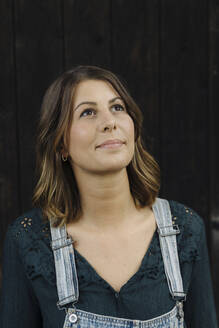 Portrait of a confident young woman in front of a wooden wall - GUSF04232