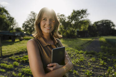 Lächelnde junge Frau mit Tablet auf einem Bauernhof auf dem Lande - GUSF04261