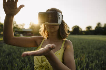 Junge Frau mit VR-Brille in einem Getreidefeld auf dem Lande - GUSF04281
