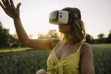 Junge Frau mit VR-Brille in einem Getreidefeld auf dem Lande - GUSF04282