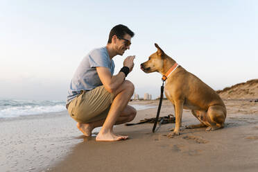 Mann verbringt seine Freizeit mit seinem Hund am Strand - EGAF00593