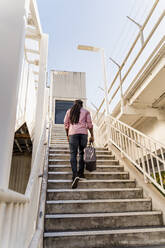 Junger Afroamerikaner mit Tasche auf einer Treppe in Miami, Florida, USA - MAUF03484