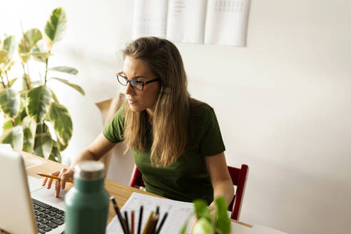 Female entrepreneur using laptop on desk in home office - VABF03206