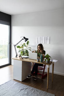 Geschäftsfrau arbeitet an einem Laptop auf einem Schreibtisch im Heimbüro - VABF03214