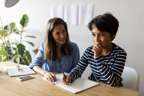 Tutorin hilft Jungen bei den Hausaufgaben zu Hause - VABF03244