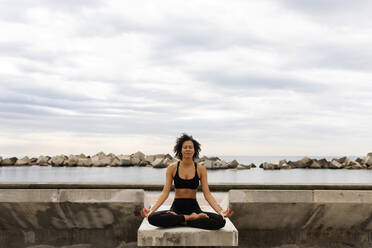 Mid adult woman with eyes closed meditating on promenade against sea - VABF03282