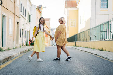 Smiling friends walking together on road in city - DCRF00554