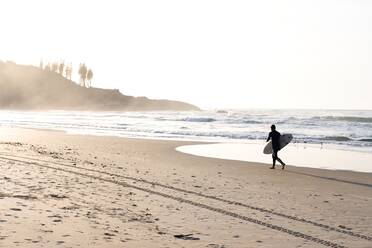 Unbekannter Mann läuft mit Surfbrett am Strand - CAVF87459