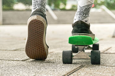 Nahaufnahme der Beine eines Mannes in Shorts auf einem Penny-Skateboard im Freien - CAVF87482