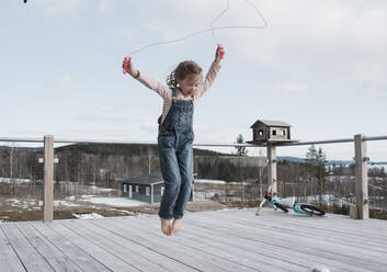 Mädchen hüpft auf ihrem Balkon in Schweden - CAVF87585