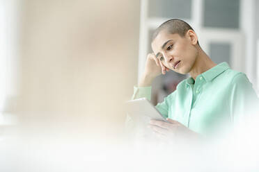 Focused businesswoman using tablet in loft office - KNSF08205
