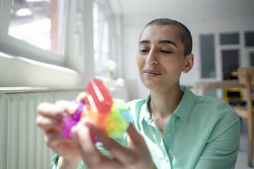 Portrait of a confident woman holding a cube game in loft office - KNSF08214