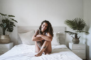 Red-haired tattooed woman in lingerie at home near the window