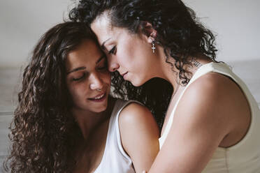 Close-up of girlfriends romancing while sitting at home - EBBF00468