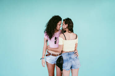 Romantic lesbian couple embracing while standing against blue wall in city  stock photo