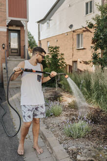 Mann bewässert Pflanzen im Garten - SMSF00058