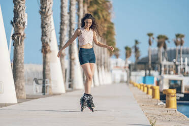 Young woman inline skating on waterfront promenade - DLTSF00880