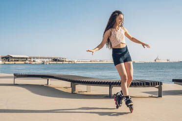 Young woman inline skating on waterfront promenade - DLTSF00881