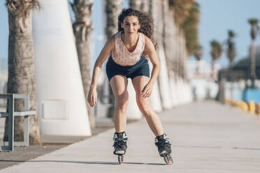 Young woman inline skating on promenade at the coast - DLTSF00885