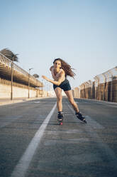 Young woman inline skating on boardwalk at the coast - DLTSF00894