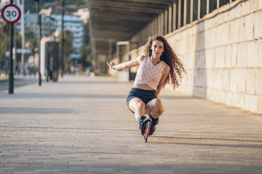 Young woman inline skating on promenade at the coast - DLTSF00896