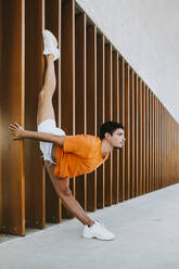 Junger Mann bei rhythmischer Gymnastik an einem Bauwerk in der Stadt - MIMFF00112