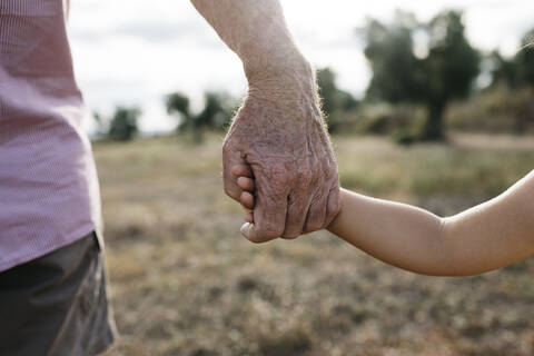 Close-up of grandfather and granddaughter holding hands stock photo