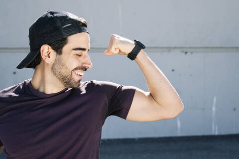 Close-up of man with eyes closed flexing muscle against wall in city stock photo