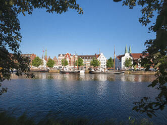 Deutschland, Schleswig-Holstein, Lübeck, Boote am Ufer der Trave mit den Gebäuden von Travemünde im Hintergrund - HAMF00692