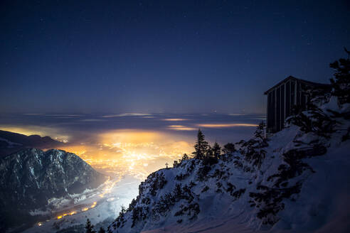 Abgeschiedene Berghütte bei Nacht mit beleuchtetem Tal im Hintergrund - MALF00022