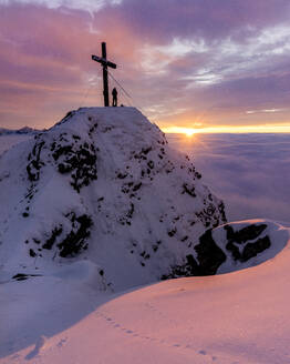 Silhouette einer Frau, die den stimmungsvollen Sonnenuntergang am Kreuz auf dem Gipfel des Aggenstein bewundert - MALF00027