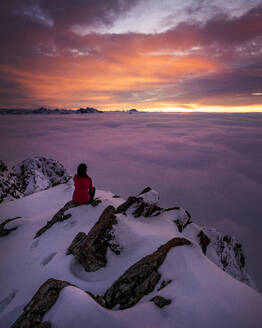 Frau bewundert stimmungsvollen Sonnenuntergang vom schneebedeckten Gipfel des Aggenstein - MALF00028