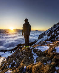 Mann bewundert den Sonnenaufgang über einem nebelverhangenen Bergtal - MALF00044