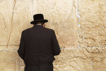 A Jewish man wearing Orthodox clothing prays by the Western Wall (Wailing Wall), Jerusalem, Israel, Middle East - RHPLF16798