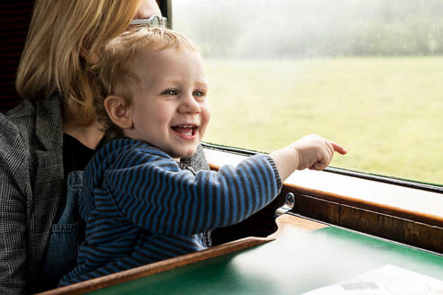 Zweijähriger Junge und Mutter in altem Dampfzugwagen, der aus dem Fenster zeigt, Bluebell Railway, Sussex, England, Vereinigtes Königreich, Europa - RHPLF16922