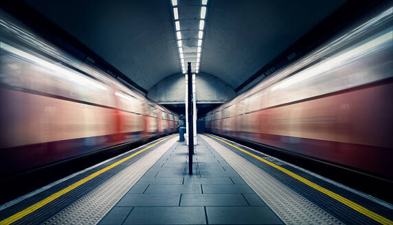 Zwei fahrende Züge und ein sitzender Pendler an der London Tube Station, Clapham Common, Clapham, London, England, Vereinigtes Königreich, Europa - RHPLF16923