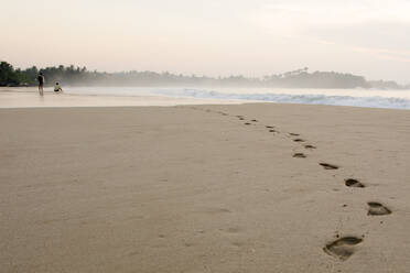 Zwei Männer beobachten den Sonnenaufgang am Strand von Talalla, Sri Lanka, Asien - RHPLF16930