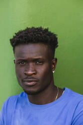 Close-up of African young man against green wall - LJF01699