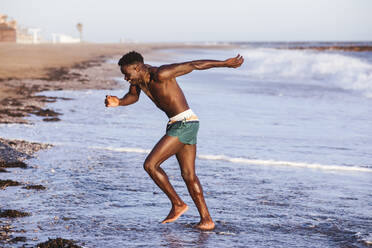 Shirtless young man exercising at shore - LJF01703