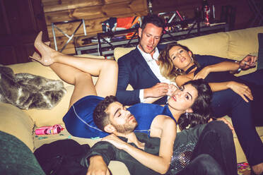 Betrunkene männliche und weibliche Freunde ruhen sich auf dem Sofa einer Party aus - EHF00669