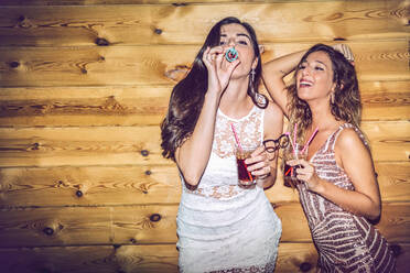 Betrunkene Freundinnen mit Requisiten und Getränken, die auf einer Party an der Wand stehen - EHF00698