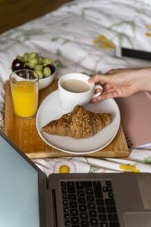 Ausgeschnittenes Bild einer Frau mit Kaffee und Laptop im Schlafzimmer - AFVF06852