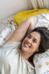 Smiling woman relaxing in bedroom - AFVF06864